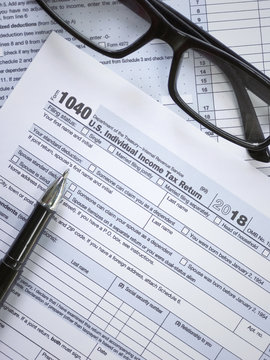 United States federal income tax return IRS 1040 documents, with pen and eyeglasses.