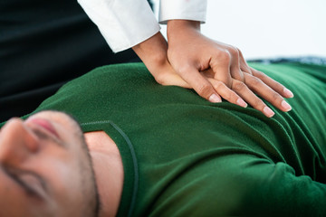 Rescuer hands doing emergency CPR on heart attacked man trying to save his life.