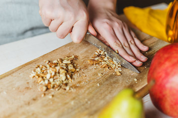 Hostess chops walnut on a wooden salad board - home cooking