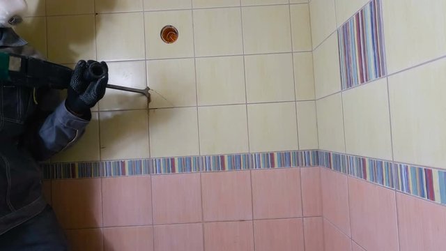 Demolition of old tiles with jackhammer. Renovation of old walls in the bathroom or kitchen