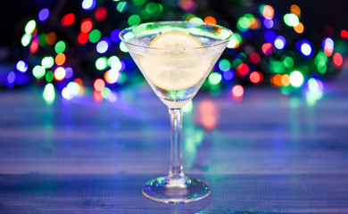 Cocktail glass with water and slice of lemon defocused garland lights. Detox drink to feel better. Hangover and detox. Detox after winter party. Health care concept. What to drink on christmas party
