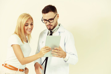 Male doctor and female patient looks at tablet computer for health data record. Healthcare and...