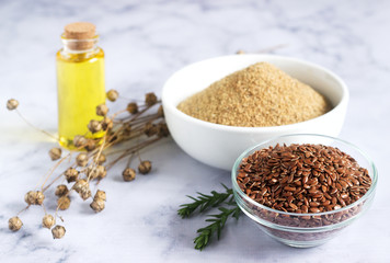 Flax seeds, flax flour, oil with sprouts and flax seed boxes on a light background.