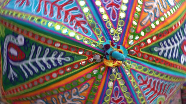Beautiful umbrella or parasol highly decorated with intricate embroidery, mirror and bead work in Pushkar, Rajasthan, India. Colorful umbrella rotates with the hands, close up
