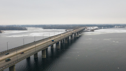 Naklejka premium Aerial top view on road bridge across the Dnieper River in Dnipro city at winter time. (Dnepr, Dnepropetrovsk, Dnipropetrovsk). Ukraine.