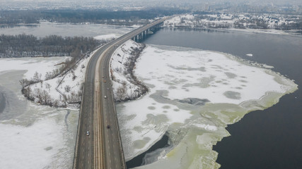 Aerial top view on road bridge across the Dnieper River in Dnipro city at winter time. (Dnepr, Dnepropetrovsk, Dnipropetrovsk). Ukraine.
