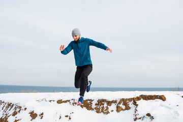 Young male runner training outdoors in winter times, man run on the snow 