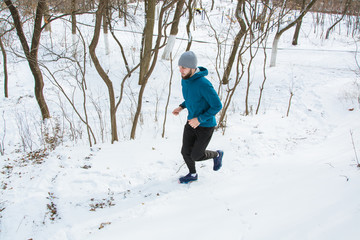 Young male runner training outdoors in winter times, man run on the snow 