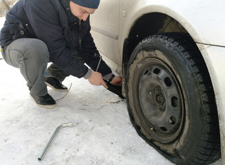 Fototapeta na wymiar Punched and flat tire on the road. Replacing the wheel with a jack by the driver