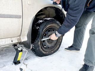 Punched and flat tire on the road. Replacing the wheel with a jack by the driver