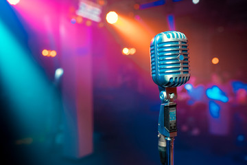 Close up retro microphone with musician playing acoustic guitar on band in night concert background