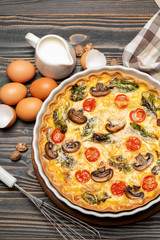Baked homemade quiche pie in ceramic baking form, eggs and cream