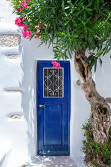 Typische Griechische Architektur auf den Kykladen: blaue Tür an weißem Haus mit bunten...