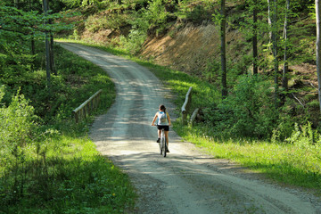 Dziewczyna na rowerze jadąca leśną drogą