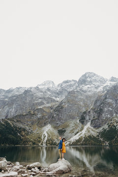 Lovely couple travelling together in the mountains, walking around the lake Morskie oko in Tatry. Amazing girl in yellow dress. Stunning view. © Shumanskyi Yurii