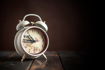 white retro alarm clock idolated on colorful background on wood surface b