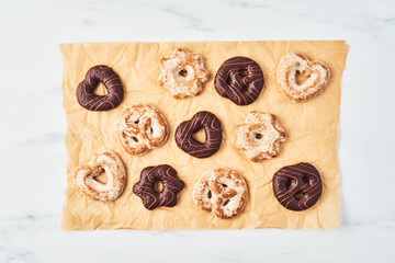 Freshly baked Christmas gingerbread cookies with chocolate icing on parchment or baking paper over white marble table. Top view. Copy space for text.