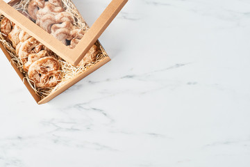 Fresh Christmas gingerbread cookies with icing in partially open gift box over white marble table. Top view. Copy space for text.