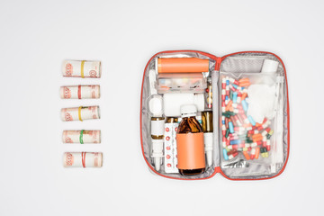 Obraz premium top view of money rolls and first aid kit with medicine isolated on grey