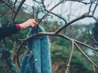 Woman picking up jumper hanging from tree