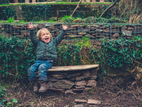 Happy little toddler on bench in garden
