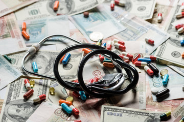 close up of colorful pills and stethoscope on cash background