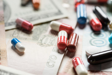 selective focus of bright pills on money background
