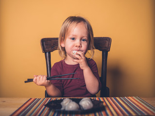Little toddler eating dim sum with chop sticks