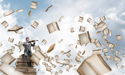 Handsome violinist sitting on book and play his melody