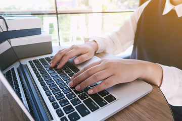 Man working by using a laptop computer on wooden table. Hands typing on a keyboard.