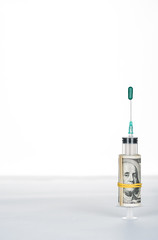 money roll and syringe with green oval pill on needle isolated on white