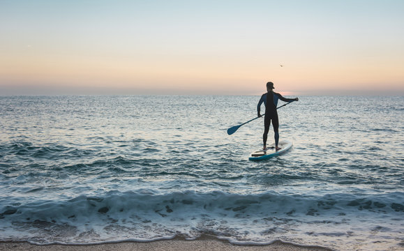 Man practicing paddle surfing with neoprene in a sunrise