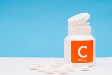 Vitamin C bottle with tablets on blue background