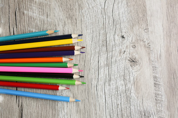Color pencils with sharpener lying on wooden natural background. Back to school concept. Colorful art studying and painting process. Drawing with pencils. Copy space place for postcard wish.