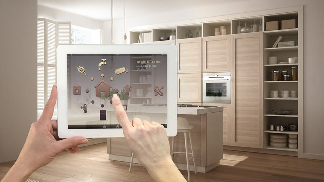 Smart remote home control system on a digital tablet. Device with app icons. Modern kitchen with wooden details in contemporary apartment background, architecture interior design