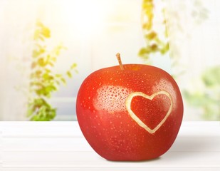 Red apple with a heart shaped cut-out on backgrouund