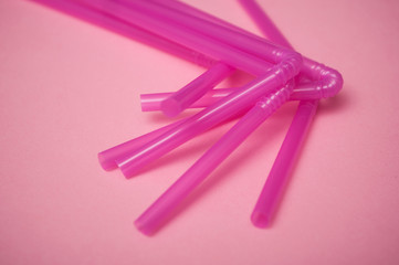 closeup of pink plastic straw collection on pink background