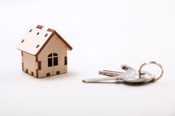 Wooden miniature house with door keys close up. Real estate concept. Small toy wooden house with keys with copy space