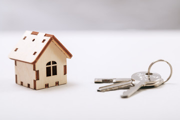 Wooden miniature house with door keys close up. Real estate concept. Small toy wooden house with keys with copy space