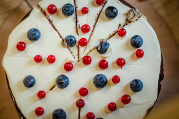 white cake with berries cut into three slices. Top view