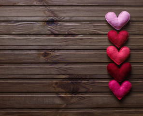 Red, pink felted hearts on the wooden background. Right side arranged 