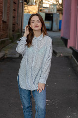 Stylish cheerful young woman dressed in white t-shirt with strolling in street of modern city. Colorful promotional background