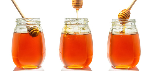 three glass jars with honey and wooden spoons for honey
