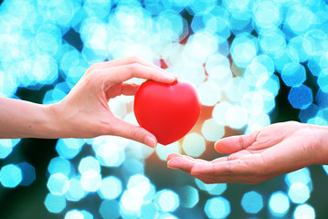 Friend 's hand give red heart to encourage loser with sunset abstract bokeh background