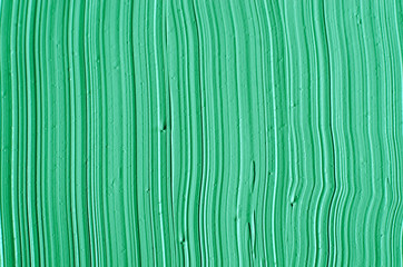 Green cosmetic clay (facial mask, cream, body scrub) texture close up, selective focus. Abstract background with brush strokes.