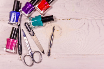 Different manicure tools and nail polishes on wooden table. Top view