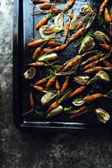 Roasted fennel and baby carrots on tray. Rustic background.
