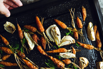Roasted fennel and baby carrots on tray. Rustic background.