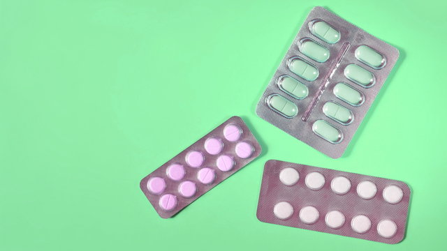 Blisters of different pills on green background. Copy space for text