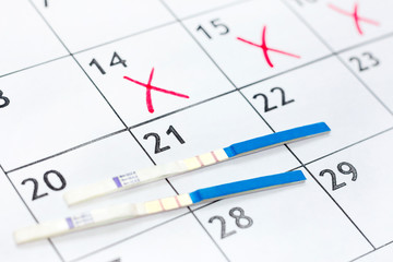 Two positive pregnancy test on calendar background. medical health care concept